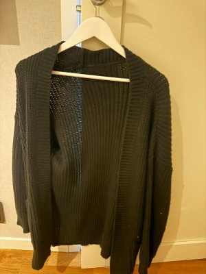 Svart stickad kofta med fickor - Säljer en svart, grovstickad kofta med öppen front och två fickor. Aldrig använd