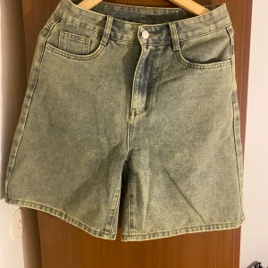 Ljusblå denimshorts från Dazy - Snygga ljusblå denimshorts från Dazy med klassisk femficksdesign och raka ben. Shortsen har hög midja, bälteshällor och stängs med knapp och dragkedja. Perfekta för en chill sommarlook.