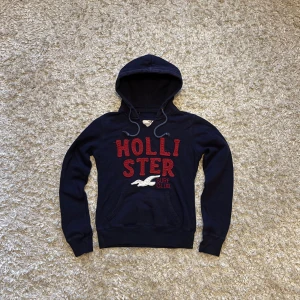 Mörkblå hoodie från hollister - Fet mörkblå hoodie från hollister med snygga detaljer. Gott skick utan defekter. Storlek M, tveka inte på o skriva vid fler frågor!