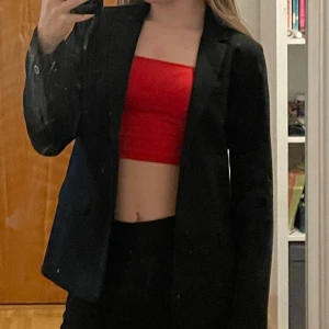 Röd bandeau tubtopp croppad - Säljer en röd bandeau tubtopp som är croppad och axelbandslös. Toppen har en enkel och stilren design med rak kant upptill och nedtill. Materialet är mjukt och stretchigt, perfekt för att skapa en cool och trendig look. Passar dig som gillar att sticka ut med färg.