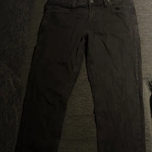 Svarta jeansbyxor i slim fit - Svarta jeansbyxor med klassisk och smal passform. Byxorna har normal midja och är tillverkade i ett stretchigt bomullsmaterial för extra komfort. Perfekta för dig som gillar en stilren och enkel look.