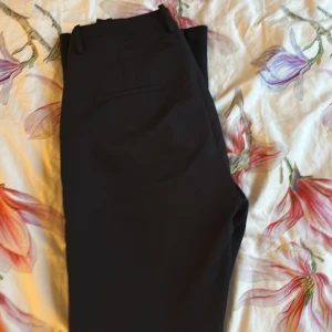 Svarta kostymbyxor från Bik Bok - Svarta trendiga kostymbyxor från Bik Bok i klassisk modell med mid waist och lite utsvängda ben. Byxorna har två bakfickor och stängs med dragkedja och knapp. Perfekta för en clean och stilren look. Säljer då dom är för stora, dom är knappt använda.