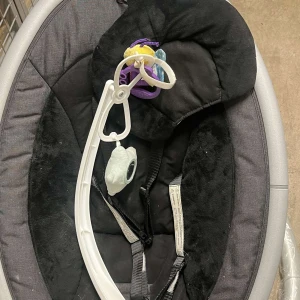 4moms mamaRoo 4 Baby Swing - Elektrisk babysitter med flera rörelseinställningar och ljudfunktioner. Selen och huvudstödet är intakta, men tyget visar visst slitage och fläckar. Kontrollpanelen är hel och leksaksbåge medföljer. Perfekt för att lugna och underhålla din bebis.