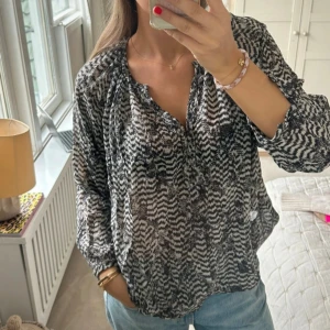  blus Isabel Marant x H&M - Snygg blus från Isabel Marant pour H&M i svartvitt mönster. Blusen har lös passform, långa ärmar och v-ringning med knappar framtill. 