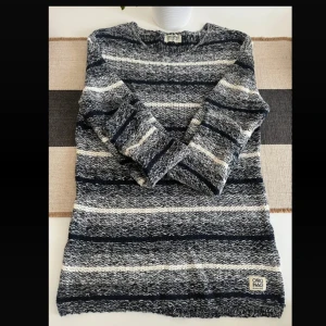 Vintage Randig stickad tröja Jack & Jones - Mysig stickad tröja från Jack & Jones Originals i marinblått, grått och vitt. Tröjan har ett randigt mönster, rund halsringning och långa ärmar. Perfekt för kyliga dagar och enkel att matcha med jeans eller chinos. Använd endast en gång.