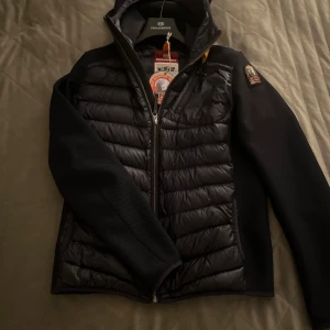  Parajumper Nolan cardigan - Snygg svart pufferjacka fràn Parajumpers med huva och quiltad framsida och rygg. Oanvänd med galja och lappen kvar! Perfekt för kyliga dagar och riktigt stilren look.