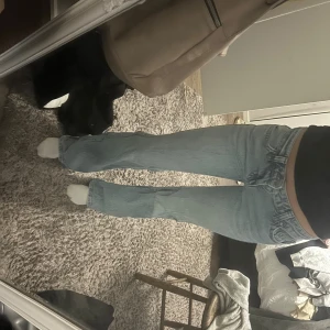 Ljusblå bootcut jeans från Gina - Säljer ett par ljusblå Gina jeans med klassisk bootcut passform och låg midja. Jeansen har fem fickor, snygga sömmar och är tillverkade i mjukt denim. Perfekta för dig som gillar retrovibbar och vill ha en cool siluett. Lite slitage längst ner 