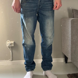 Blå jeans från G-Star RAW - Säljer ett par blå jeans från G-Star RAW med snyggt slitna detaljer och markerade sömmar vid knäna. Jeansen har klassisk femficksdesign, normal passform och är tillverkade i bomull. Perfekta för dig som gillar en avslappnad och modern look.