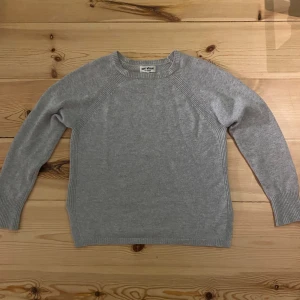 Ljusgrå kashmirtröja från Soft Goat - Supermjuk ljusgrå tröja i 100% kashmir från Soft Goat. Klassisk rund halsringning, ribbade muddar och lång ärm. Perfekt för dig som gillar stilren och enkel design med lyxig känsla.