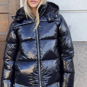 Svart glansig pufferjacka med huva - jag säljer denna fina trendiga jacka från nelly som har använts en gång! pris kan diskuteras😝❤️