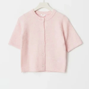 Ljusrosa stickad kofta med pärlknappar - Superfin ljusrosa stickad kofta med korta ärmar och rund hals. Koftan har pärlknappar framtill och en mjuk, fluffig känsla. Storlek 158/164. Finns ej att köpa längre. Använd 1-2 ggr. Skriv för fler frågor/ bilder🩷