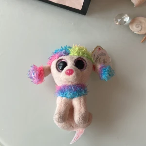 Ett godsedjur som är en nyckelring - En nyckelring med en hund som har färgglad päls. Perfekt för barn och vuxna som gillar färger och gosedjur.