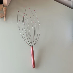 Huvudmassagerare - Avslappnande huvudmassagerare med metalltrådar och rosa toppar. Ergonomiskt handtag i rosa metall. Perfekt för stresslindring och massage. Produkten är i gott skick utan synligt slitage eller defekter.