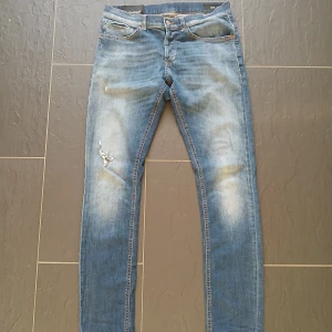 Dondup jeans - Säljer ett par blåa dondup jenas med slitningar och hål på ena benet. George model. Jeansen har en tvättad look och sitter slim fit. Modellen är 184 cm. Hör av dig vid minsta fråga!