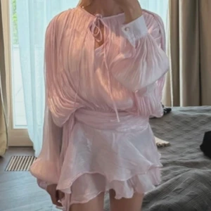 Ljus rosa mini klänning från Miss Rosier - Superfin ljusrosa kortklänning med omlott-design och volangkantad kjol från Miss Rosier. Har under shorts som med kommer. Aldrig använd. 