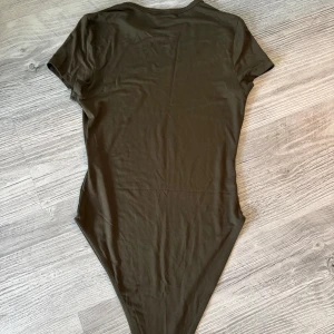 Olivgrön kortärmad bodysuit  - Olivgrön bodysuit från SHEIN den är använd 3 gånger. 