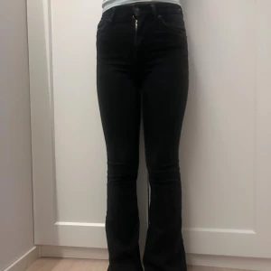 Svarta bootcut jeans med hög midja - Säljer ett par svarta jeans med bootcut och hög midja. Jeansen har klassisk femficksdesign, dragkedja och knapp framtill. Materialet är stretchigt och sitter snyggt över höfterna och låren innan de går ut vid bensluten. Perfekt för dig som gillar en tidlös och cool look. Jensen är uppsydda. Jag är 160 cm lång och de är perfekt lång för mig. Skulle säga byxorna är lite små i storlek. Det går att buda på❤️
