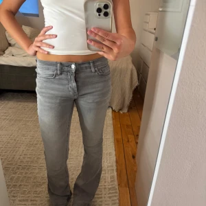 Grå bootcut jeans - Säljer ett par grå jeans från Ginatricot. Lite slitna längst nere då jag råkat gå på dem, se bilder. 