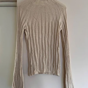 Beige ribbad stickad tröja Wera XS - Säljer en beige ribbad stickad tröja från Wera i storlek XS. Tröjan har långärmad design, smal passform och är tillverkad i ett mjukt stickat material. Perfekt för lager-på-lager och har en clean, minimalistisk look.