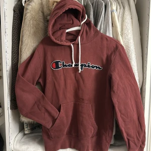 Brun hoodie från Champion med broderi - Säljer en brun hoodie från Champion i storlek medium. Tröjan har stor broderad logga på bröstet, vit snörning i huvan och en klassisk känguruficka. Mjuk insida och skön passform, perfekt för chill dagar.