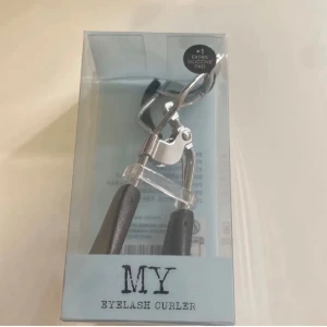 MY Eyelash Curler med extra silikonpad - Säljer en ögonfransböjare från MY i metall med svarta handtag och en extra silikonpad. Perfekt för att få snygg böj på fransarna och ge ögonen ett lyft. Kommer i originalförpackning.