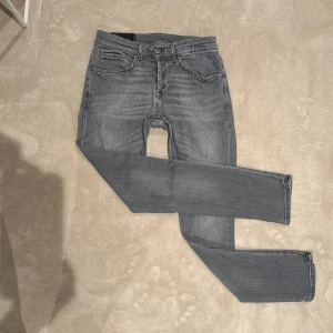Grå straight jeans från Dondup - Säljer ett par grå skinny jeans från Dondup i storlek 31. Jeansen har klassisk femficksdesign, snygga slitningar och Dondup-logga baktill. De är tillverkade i stretchig bomullsdenim för en tight och bekväm passform. Och är i hyfsat bra skick (De är lagade vid skrevet men inget man tänker på) 