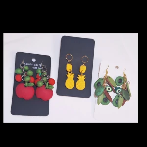 3 par örhängen i Polymerclay "Ätbart 2" - Tre par handgjorda örhängen i form av frukter: röda äpplen med gröna detaljer, gula ananas och gröna avokado med bruna och svarta inslag. Alla örhängen har lekfull design och är tillverkade i polymerlera med metallfästen. Perfekt för dig som gillar unika och färgstarka accessoarer. Allergivänligt ❤️