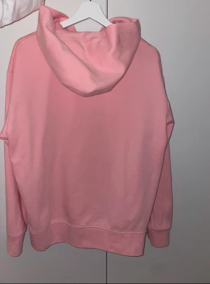 Rosa hoodie från Polo Ralph Lauren - Säljer en ljusrosa hoodie från Polo Ralph Lauren med dragkedja och huva. Tröjan har ett blått Polo-logo broderat på bröstet, två fickor framtill och ribbade muddar vid ärmslut och nederkant. Perfekt för chill dagar och streetstyle. Och den är storlek L men sitter perfekt som M också.