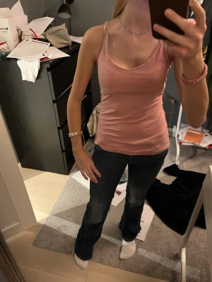 Rosa linne med smala axelband - Säljer en enkel och snygg rosa linnetopp med smala axelband och rundad halsringning. Toppen är figurnära och passar perfekt till jeans eller kjol. Mjuk och skön bomullskänsla, perfekt för varma dagar.