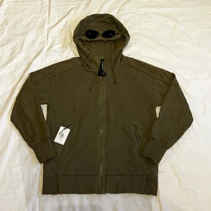 CP Company hoodie - Fet CP Company hoodie köpt från NK. Den är använd i gott skick och har även kvar orginalknappar. 