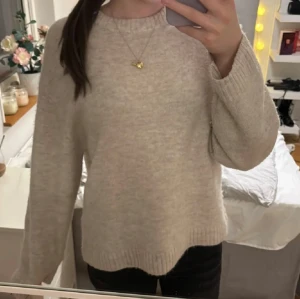 Beige stickad tröja från Gina Tricot💕 - Mysig beige stickad tröja med rundad hals och ribbade muddar vid ärmslut och nederkant. Tröjan har en loose passform och långa ärmar, perfekt för att hålla sig varm under kyliga dagar. Enkel och stilren design som är lätt att matcha med olika outfits.