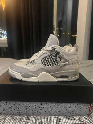Nike Air Jordan 4 Retro Neutral Grey - Nike Air Jordan 4 Retro i färgen Neutral Grey med coola silvriga detaljer och meshpaneler. Skorna har snörning, platt sula och en mix av skinn och mocka. Snyggt retro-utseende med ikoniska Air-dämpningen och Jumpman-logga på tungan. Använd endast fåtal gånger, skick 8/10