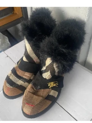 Burberry boots med svart päls - Unika Burberry boots med randigt mönster i beige, brunt och svart. De har en fluffig svart päls upptill och guldfärgade detaljer på sidan. Sulan är platt och robust, och materialet är en mix av textil och päls. Perfekt för dig som vill sticka ut med din stil. Supersnygga till vintern💕
