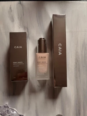 CAIA Dewy Drops Serum Foundation 10C & F13 borste - Säljer detta kit då det tyvärr var fel nyans för mig. Endast testat en gång med borsten! Nyans 10c och borsten är F13.                          AI BESKRIVNING:  CAIA Dewy Drops Serum Foundation i nyansen 10C. Kommer i en snygg frostad glasflaska med silvrig pump och bruna förpackningar. Foundationen är lätt och ger en naturlig, återfuktad finish med vitamin E och glycerin. Perfekt för dig som vill ha glow och jämn hudton.