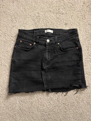 Svart jeanskjol - Svart kort jeanskjol från Gina med fem fickor och rå, fransig kant💗