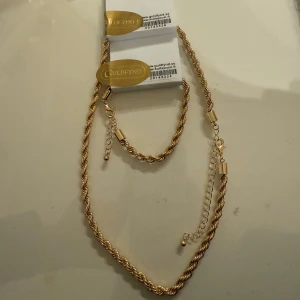 Cordell kedja från Guldfynd - Snygg guldfärgad kedja från Guldfynd med tvinnad design och justerbar längd. Kedjan har en glansig finish och robust karbinlås. Perfekt för att ge din outfit lite extra bling och passar både som halsband och armband.