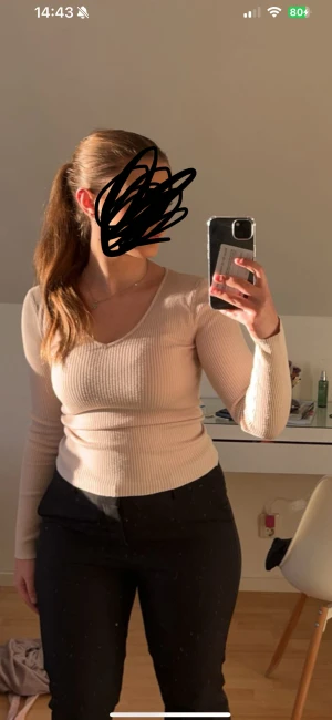 Beige ribbad v-ringad tröja  - Säljer en beige ribbad långärmad tröja från Amisu med snygg v-ringning. Tröjan är figurnära och har en mjuk, stretchig känsla som sitter skönt på kroppen. Perfekt att matcha med jeans eller kjol för en clean look. Felfri