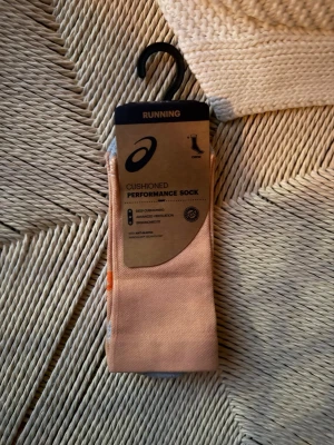 Asics performance löparstrumpor orange - Säljer ett par Asics cushioned performance socks i orange och grått, perfekta för löpning. Strumporna har avancerad ventilation, ergonomisk passform och extra dämpning. Materialet är en blandning av polyester, polyamid och elastan för bästa komfort och anti-blister teknologi. Oanvända, nypris 220kr