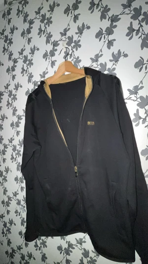 Svart boss kofta - Svart boss kofta med fin guldig luva. Fin passform, riktigt nice kofta använd fåtal gånger