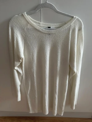 Vit stickad långärmad tröja från H&M - En enkel och stilren vit stickad tröja från H&M med rund halsringning och långa ärmar. Tröjan har en mjuk och lite grovstickad struktur, ribbade muddar vid hals och ärmslut samt en rak passform som är lätt att matcha med jeans eller kjol