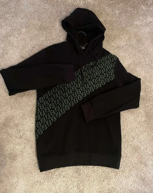 FËNDÏ Hoodie  - Svart Hoodie med Grön Loga. 