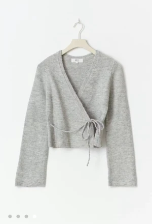 Grå omlottkofta från Gina Tricot - Säljer en ljusgrå omlottkofta från Gina Tricot med knyt i sidan GAMLA MODELLEN (tjockare ”snören”). Precis som ny då jag andvänt den ca 5 gånger (förra vintern). Känner att det inte längre är min stil men hade 100% passat dig. Jag är 156 och tröjan är lite croppad.