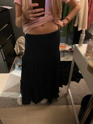 Marinblå långkjol - En marinblå långkjol i luftig och lätt bomull. Kjolen har en flowy passform med flera volanger och en enkel, stilren look. Perfekt för dig som gillar en avslappnad och trendig stil. Midjemodellen är rak och kjolen är helt enfärgad. Köpt för 350 och använd 1 gång