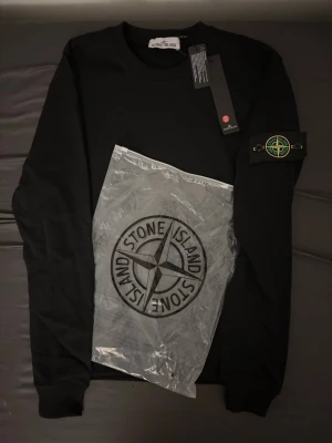 Stone Island sweater - Svart sweatshirt från Stone Island i storlek M. Klassisk rund hals och ribbade muddar. Ikonisk Stone Island patch på vänster ärm och stor logga på framsidan. Mjuk bomullskvalitet som är skön att bära. Perfekt för dig som gillar streetwear och snygga detaljer. PRISET KAN DISKUTERAS 