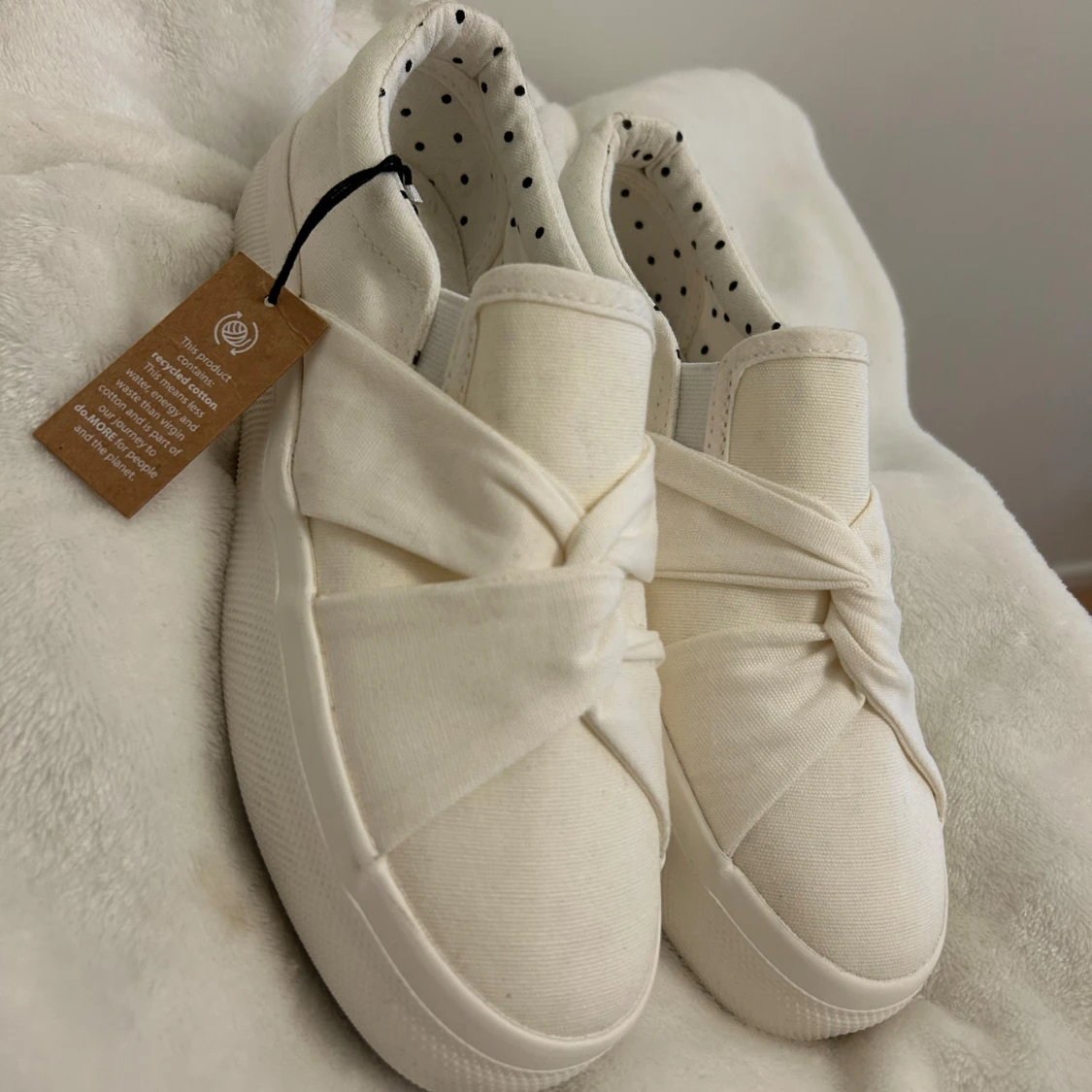 Vita slip-on sneakers med knut