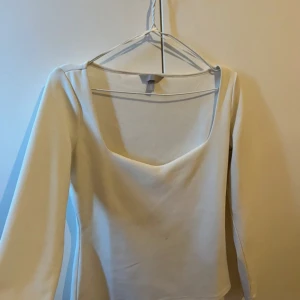 Vit långärmad topp från H&M - Snygg vit långärmad topp från H&M med fyrkantig ringning. Toppen har en clean och enkel design som passar till många olika looks.