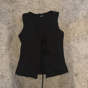 Svart topp med snörning från Gina Tricot - Svart topp från Gina Tricot i storlek XS. Toppen har v-ringning och snörning framtill.💕