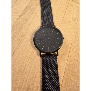 Svart klocka Black Oak Sweden Lunar - Stilren svart klocka från Black Oak Sweden, modell Lunar. Klockan har en rund urtavla med minimalistiska silvriga index och svart mesh-armband i metall. Vattentålig upp till 3 ATM. Perfekt accessoar för dig som gillar en clean look obs batteri behövs 