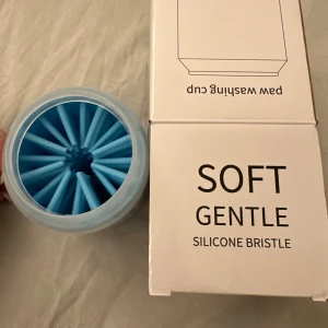 Paw Washing Cup Soft Gentle Silicone Bristle husdjur tass  - Effektiv och skonsam tassrengörare för hundar med mjuka silikonborstar. Enkel att använda – tillsätt vatten, för in tassen och vrid för noggrann rengöring. Produkten är i nyskick och levereras i originalförpackning.