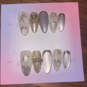 XS - Press-on naglar i guld och silver - Snygga press-on naglar i mandelform med vit, silver och guldig bas. Dekorerade med glittriga detaljer, 3D-blommor och blad i guld. Perfekt för dig som vill ha en lyxig och trendig look utan att gå till salong. 